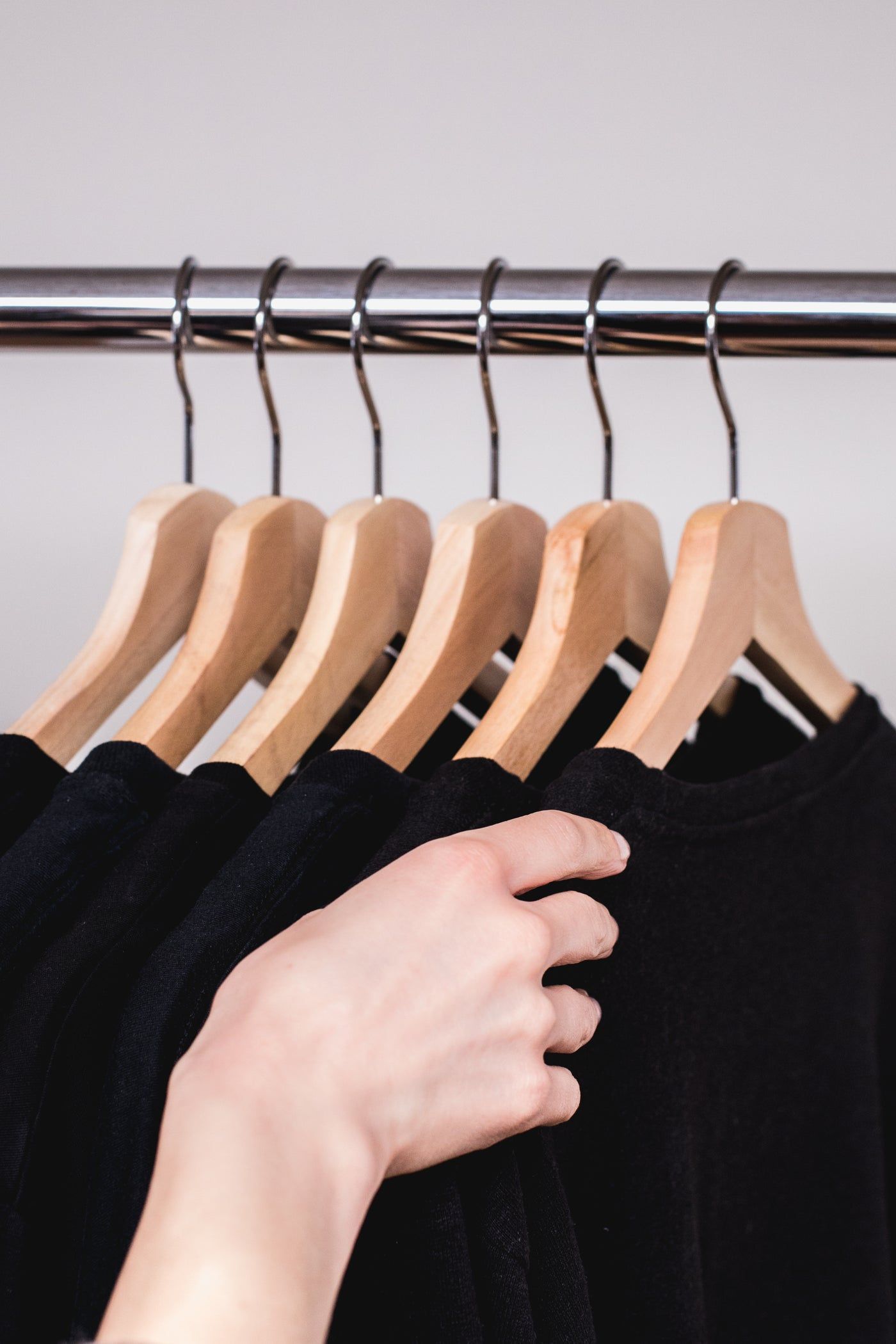 Main qui attrape un sweat noir sur un portant