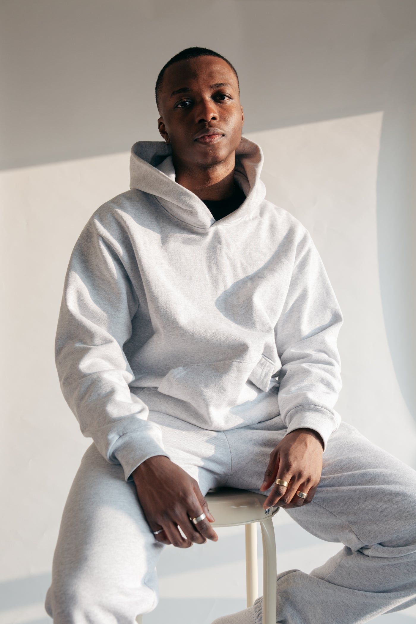 Homme assis en hoodie et jogging gris cendre